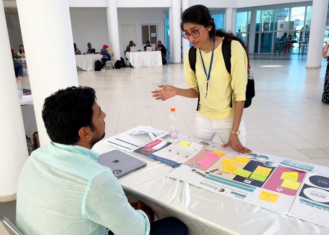 Ibrahim Mahgoub at The Rockefeller Foundation booth speaking with a participant at the 2022 Deep Learning Indaba in Tunis, Tunisia. Photo by Matt Freeman, The Rockefeller Foundation.